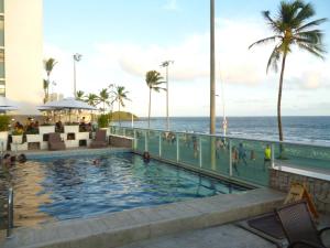 a swimming pool with the ocean in the background at Bahia Flat 117 in Salvador