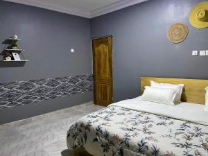 a bedroom with a bed and a blue wall at Tamani - Your home away from home in Tamale