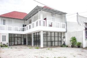 een wit huis met een rood dak bij Samar Wulu Guest House Syariah Mitra RedDoorz near Ketapang in Ketapang