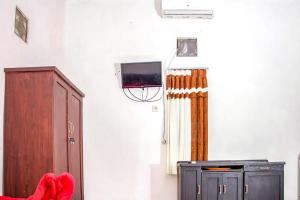 a room with a tv on the wall and a cabinet at Samar Wulu Guest House Syariah Mitra RedDoorz near Ketapang in Ketapang