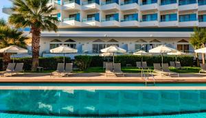 a hotel with a swimming pool with chairs and umbrellas at Blue Sea Beach Resort in Faliraki