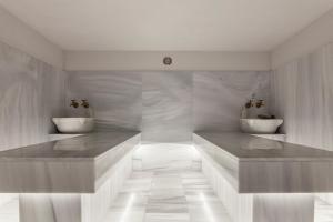 a white bathroom with two sinks and marble floors at Blue Sea Beach Resort in Faliraki