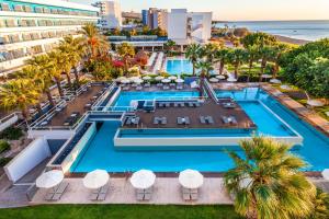 an aerial view of a resort pool with palm trees and the ocean at Blue Sea Beach Resort in Faliraki