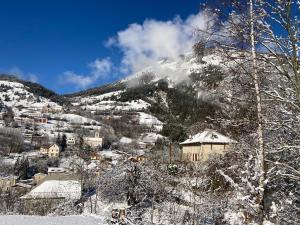 een dorp bedekt met sneeuw met een berg op de achtergrond bij Au Diapason Chambres d'hôtes montagne in Auzet