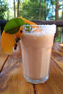 a drink sitting on a wooden table with an orange at Sky Island Studios in Mount Tamborine