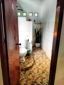 baño con aseo y suelo de baldosa. en Sumatra Orangutan Discovery Villa, en Bukit Lawang