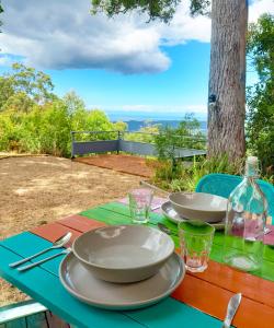 a picnic table with plates and glasses and a bottle at Sky Island Studios in Mount Tamborine