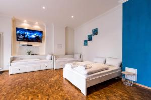 a living room with two white beds and a blue wall at DR Apartments Friedrichshain in Berlin