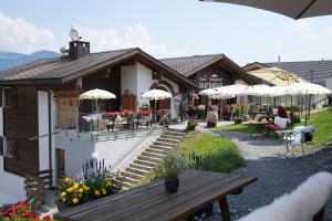 a building with a picnic table and tables and umbrellas at Hotel Surselva in Surcuolm
