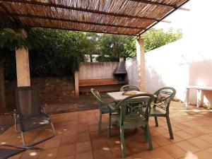 un patio con mesa y sillas bajo una pérgola en Rouvenac 