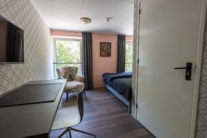 een slaapkamer met een bed, een bureau en een stoel bij Hotel Leeuwerik in Bad-Nieuweschans