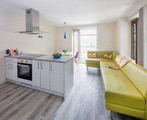 a living room with a yellow couch and a kitchen at The Crows Nest - UCC Summer Beds in Cork