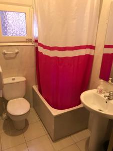 a bathroom with a toilet and a red shower curtain at Hostal Muntaner in Barcelona