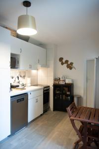 a kitchen with white cabinets and a table and a wooden floor at Les Gites By Carpe Diem in Les Andelys