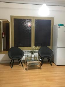 2 sillas y una mesa en una habitación con 2 ventanas en Hostal Muntaner, en Barcelona