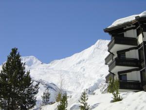 a building with a snow covered mountain in the background at Haus Allegra Panorama in Saas-Fee