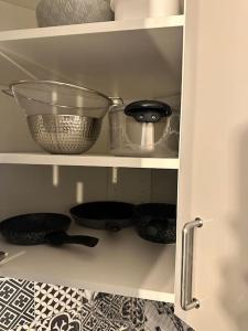 a kitchen cabinet with bowls and other kitchen utensils at Studio moderne proche Disney Land in Bussy-Saint-Georges