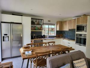 a kitchen with a wooden table and a large refrigerator at 90 Mile Beach Escape in Seaspray