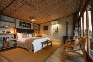 Cheetah Ridge Lodge في نامبيتي جيم ريسيرف: غرفة نوم بسرير كبير وكرسي