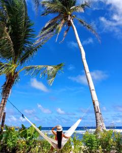 a man laying in a hammock under two palm trees at Bamboo Surf Beach in San Isidro