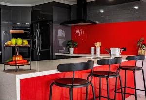 una cocina con paredes rojas y negras y taburetes de bar en The Gums Anchorage, en Bellara