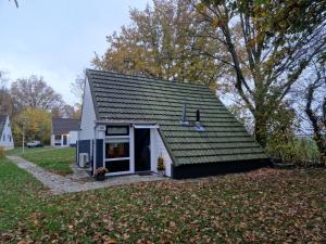 a small house with a black roof on a yard at Huuske 086 in Simpelveld