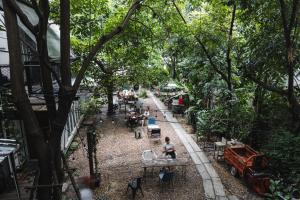a group of people sitting at tables in a garden at The Yard Bangkok Hostel in Bangkok