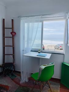 Zambujeira Lounge في زامبوجيرا دو مار: غرفة مع مكتب ونافذة مطلة على الشاطئ
