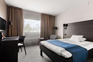 a hotel room with a large bed and a desk at Best Western Hotel Scheele in Köping