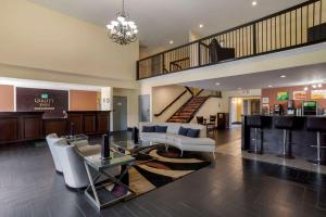 a living room with white furniture and a staircase at Quality Inn Phenix City Columbus in Phenix City