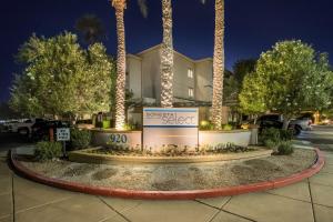 a sign in front of a building with palm trees at Sonesta Select Phoenix Chandler in Chandler