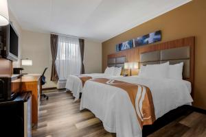 Quality Inn & Suites New Hartford - Utica في أوتيكا: غرفة فندقية بسريرين ومكتب