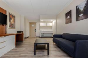 Quality Inn & Suites New Hartford - Utica في أوتيكا: غرفة معيشة مع أريكة زرقاء وطاولة