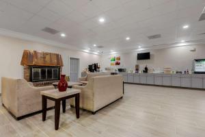Quality Inn & Suites New Hartford - Utica في أوتيكا: لوبي فيه كنب وموقد ومكتب