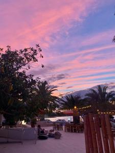 una puesta de sol en una playa con gente sentada en la arena en Hotel Tagomago, en Bahía de San Antonio