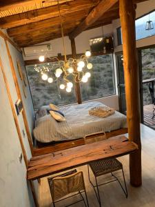 1 dormitorio con cama, mesa y lámpara de araña en Revolucionarte.Potrerillos en Potrerillos