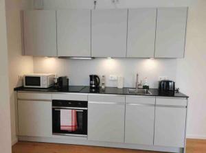 a kitchen with white cabinets and a microwave at New 1 bedroom in Kirchberg, Outdoor & Parking in Luxembourg