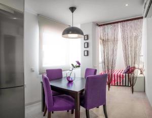 een eetkamer met paarse stoelen en een tafel bij Apartamentos Levante in Zahara de los Atunes
