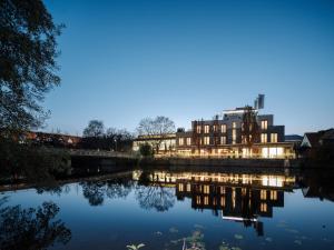 ビーティッヒハイム・ビッシンゲンにあるHotel Eberhards am Wasserの夕暮れ時の川の横の建物