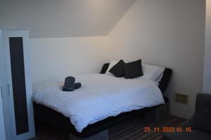 a bedroom with a bed with white sheets and black pillows at Remarkable 1-Bed Apartment in Tunbridge Wells in Royal Tunbridge Wells
