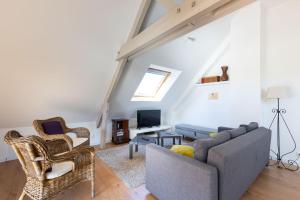 uma sala de estar com um sofá e cadeiras e uma televisão em Appartement des Grands Champs avec terrasse em Saint-Aignan