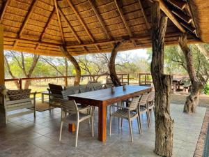 a wooden table and chairs under a wooden roof at Oryx Wilderness Game Lodge and Tented Camp 