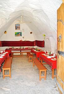 una sala da pranzo con tavoli rossi e panche di Touring Club MARHALA MATMATA a Matmata