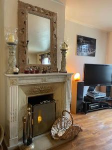 a living room with a fireplace with a mirror and a tv at Appartement sur le parvis de la cathédrale in Senlis