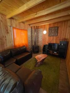 a living room with a leather couch and a desk at Cabañas El Boldo in Licán Ray