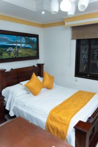 um quarto com uma cama com almofadas amarelas em Hotel Aires del Quindío Armenia em Armênia