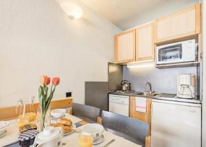 une petite cuisine avec une table avec des fleurs dessus dans l'établissement Tignes appart 4 pers /piscine/sauna/pied des pistes, à Tignes