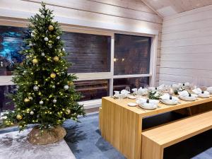 een kerstboom in het midden van een kamer met een tafel bij Santa's Luxury Boutique Villa, Santa Claus Village, Apt 2 in Rovaniemi