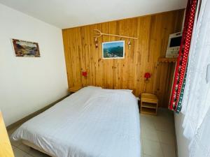 a bedroom with a white bed and wooden walls at IDEAL MONTAGNE in Le Mont-Dore