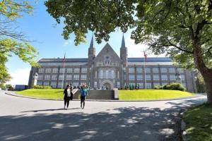 zwei Personen gehen vor einem großen Gebäude in der Unterkunft Fully equipped independent apartment near NTNU,Lerkendal og center in Trondheim + 3 Fotos